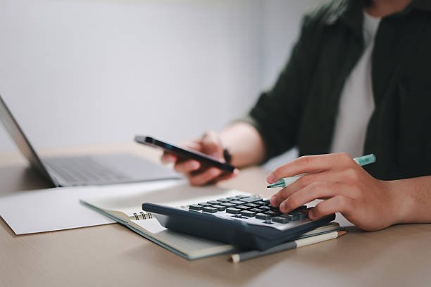 Tax file with calculator, pen, coins and glass jar